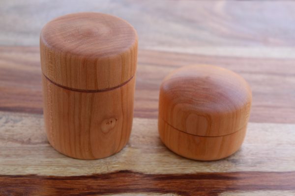 Two small cylindrical wooden lidded containers.