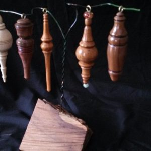 Five wooden ornaments hang from a stand in front of a black backdrop.
