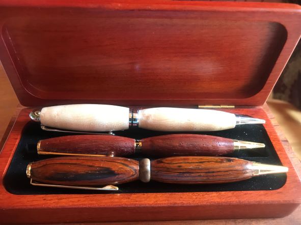 Three wooden pens sit in a wooden case.